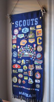 a wall hanging with patches and badges on it's side in a room next to a window