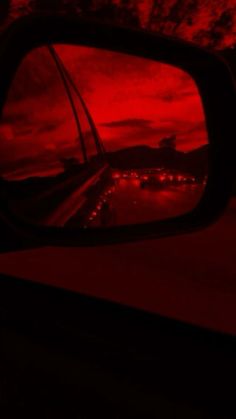 the reflection of a red sky in a rear view mirror