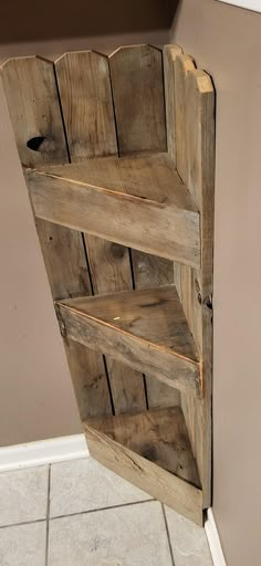 a wooden book shelf sitting on top of a white tile floor next to a wall