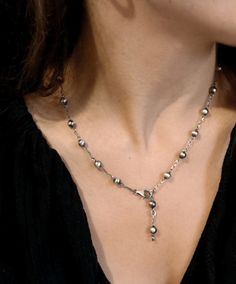 a woman wearing a necklace with pearls and silver beads on it's neckline