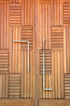 two wooden doors with metal handles and bars on the sides, in front of a wood wall