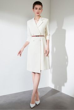 Ivory Elegance Belted Trench Dress Description: Step into a world where grace and style meet with our Ivory Elegance Belted Trench Dress. This pristine piece reimagines the classic trench coat into a sophisticated dress perfect for the modern woman. Designed with a cinched waist and a flattering A-line silhouette, this dress accentuates your form while providing a comfortable, breathable fit. The light ivory hue offers a versatile palette that transitions effortlessly from professional settings to chic social gatherings. Adorned with subtle button detailing and a sleek brown belt, this dress combines timeless fashion with a contemporary twist. Perfect for those who value elegance and poise in their wardrobe.: Key Features: Luxurious light ivory fabric for a versatile and elegant look The f Trench Dress, Ivory Fabric, Classic Trench Coat, Light Ivory, Sophisticated Dress, Brown Belt, Knee Length Dresses, Blazer Dress, Cinched Waist