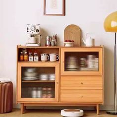 a wooden cabinet with glass doors and drawers in a living room next to a lamp