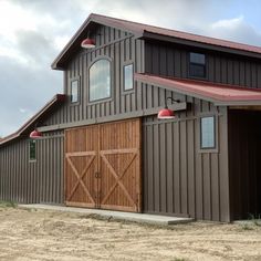 a large brown barn with a red roof and two doors on the side of it