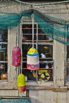 there are many different items on display in this shop window, including fishing nets and buoys