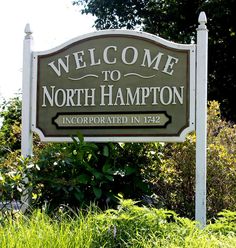 the welcome sign to north hampton is in front of some bushes and trees on a sunny day