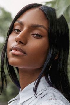 a woman with long black hair wearing a white shirt and looking off to the side