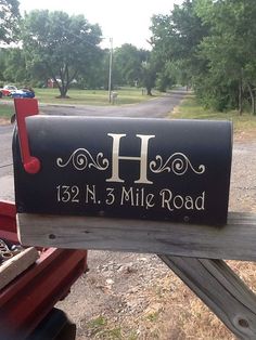 a mailbox with the letter h painted on it's side in front of a road