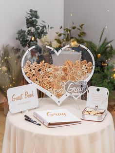 a table topped with a heart shaped sign next to a notepad and pen on top of a table