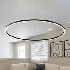 a living room filled with white furniture and a round light fixture hanging from the ceiling