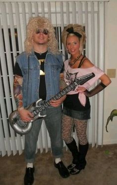 a man and woman dressed up as rockers with their guitars in front of a window