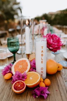 a table with oranges, grapefruits and candles on top of it