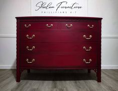 a red chest of drawers with brass handles and knobs on the bottom, against a white wall