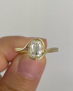 a person holding a gold ring with an oval cut diamond