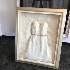 a wedding dress in a frame on the floor