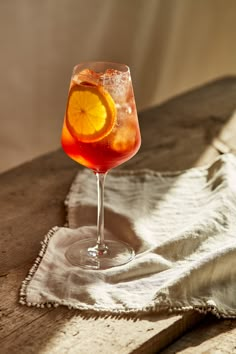 a drink with an orange slice in it sitting on a table next to a white towel