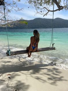 a woman sitting on a swing in the water