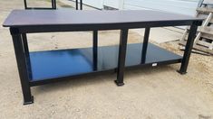 a black table with blue top sitting in front of a garage door on the side of a road