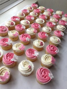 cupcakes with pink and white frosting are arranged on a table