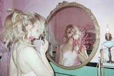 a woman standing in front of a mirror brushing her teeth