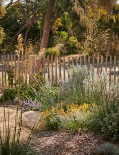 a wooden fence surrounded by plants and flowers