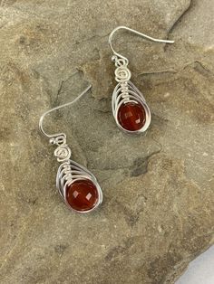 These elegant carnelian drop earrings are striking . The micro faceted surface of these genuine carnelian gemstones really catch the light and sparkles.. The color of these gemstones is burnt orange that is natural and not dyed. I chose to enhance these earrings with a woven silver wire design to let the natural beauty of the stone shine. Featuring an 8mm genuine faceted carnelian gemstone. These earrings are dainty, lightweight and perfect for everyday wear. MATERIALS * Genuine Carnelian Gemsto Carnelian Gemstone Dangle Earrings, Amber Carnelian Earrings With Ear Wire, Amber Carnelian Gemstone Earrings, Amber Carnelian Teardrop Earrings, Carnelian Drop Earrings As Gift, Pierced Carnelian Drop Earrings, Carnelian Drop Earrings For Gift, Carnelian Amber Earrings For Gift, Amber Carnelian Earrings Gift