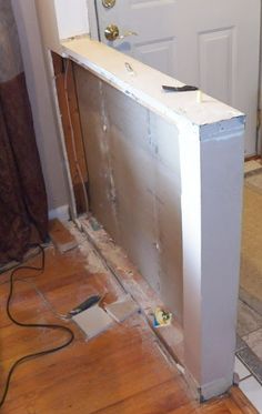 a white refrigerator sitting in the middle of a room next to a door and a hard wood floor