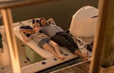 a man and woman laying on the back of a boat