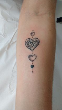 a tattoo on the arm of a woman with two hearts and a key hanging from it