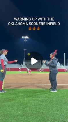 two women on a baseball field with bats and balls in their hands, talking to each other