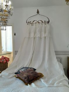 a bed with a white canopy over it's headboard and pillows on top of it