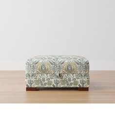 a footstool sitting on top of a wooden floor next to a white wall