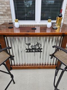 two bar stools sit in front of a metal wall with the word wine on it