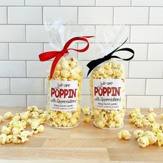 two bags of popcorn sitting next to each other on a wooden table with red ribbon