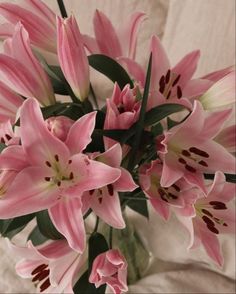 a vase filled with pink flowers sitting on top of a white cloth covered tablecloth