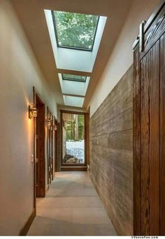 a long hallway with skylights and wooden doors leading to the outside rooms in this home