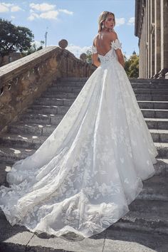 a woman in a white wedding dress standing on some steps with her back to the camera