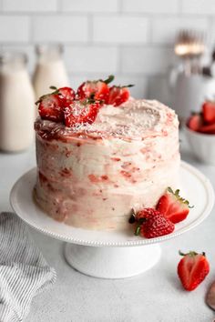 a strawberry cake with frosting and fresh strawberries on the top is ready to be eaten