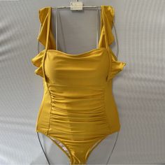 a yellow one piece swimsuit hanging on a wall