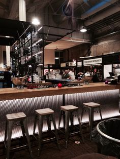 a bar with stools in front of it and people sitting at the bar behind