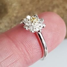 a person's finger with a ring on it that has a flower in the middle