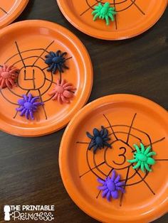 four orange plates with colorful spider webs on them and the number three in the middle