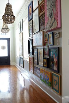 a hallway with pictures on the wall and a chandelier hanging from the ceiling