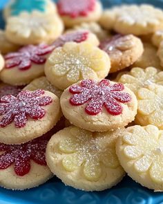 a blue plate topped with cookies covered in powdered sugar and decorated with red flowers