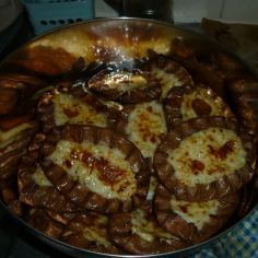 a pan filled with food sitting on top of a stove next to a blue and white checkered table cloth