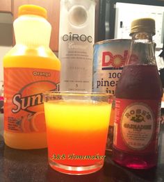 an orange drink sitting on top of a counter next to bottles