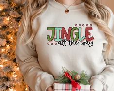 a woman holding a present in front of a christmas tree with the words jungle all the way on it