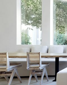 two wooden chairs sitting next to each other in front of a table with white couches