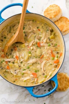 a blue pot filled with chicken and vegetable soup next to crackers on a marble surface