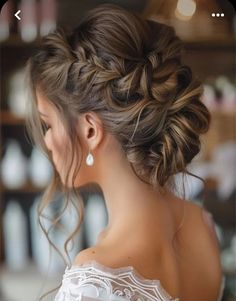 a woman with long hair wearing a white dress and braided up in a low bun